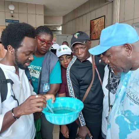Group of researchers examining mosquito larvae and pupae in a blue basin