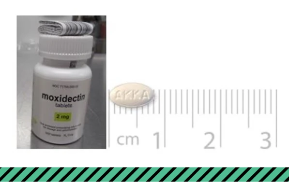 A bottle of moxidectin and a pill placed on a centimeter ruler for scale.